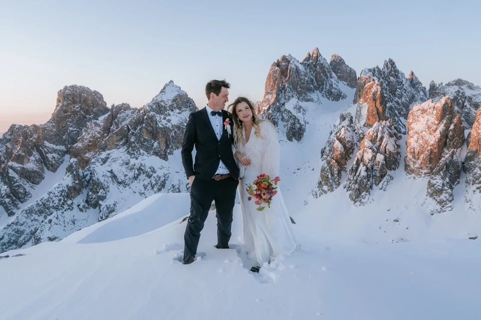 The couple in the snow as the Tre Cime area spires glow at sunrise