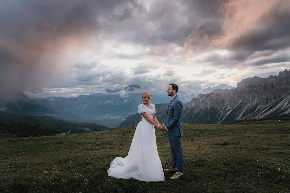 The couple on the meadow at Passo Giau under a dramatic evening sky