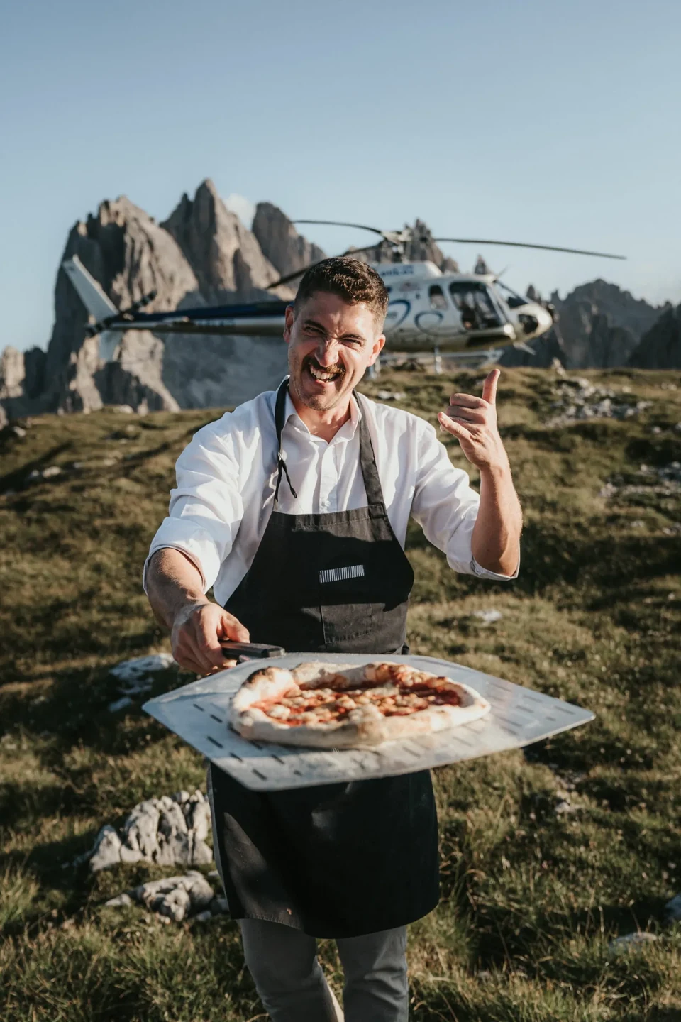 A chef making fresh pizza on the mountain, the helicopter behind