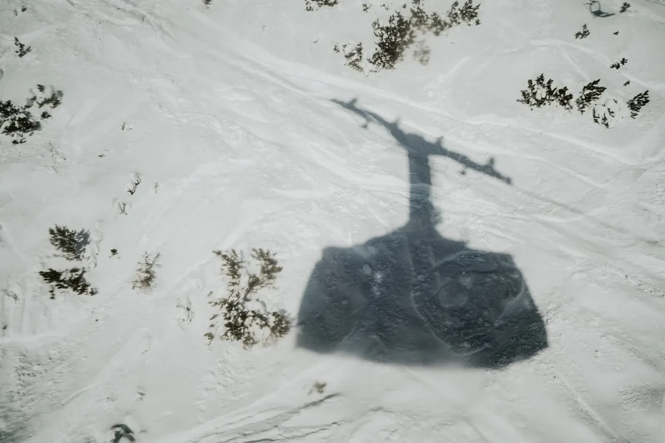 The shadow of the cable-car cabin cast on the snow below