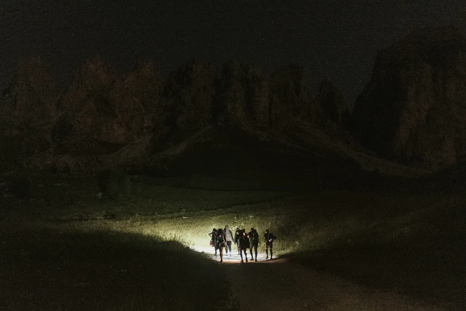 The group lit only by a head-torch beam on the dark trail