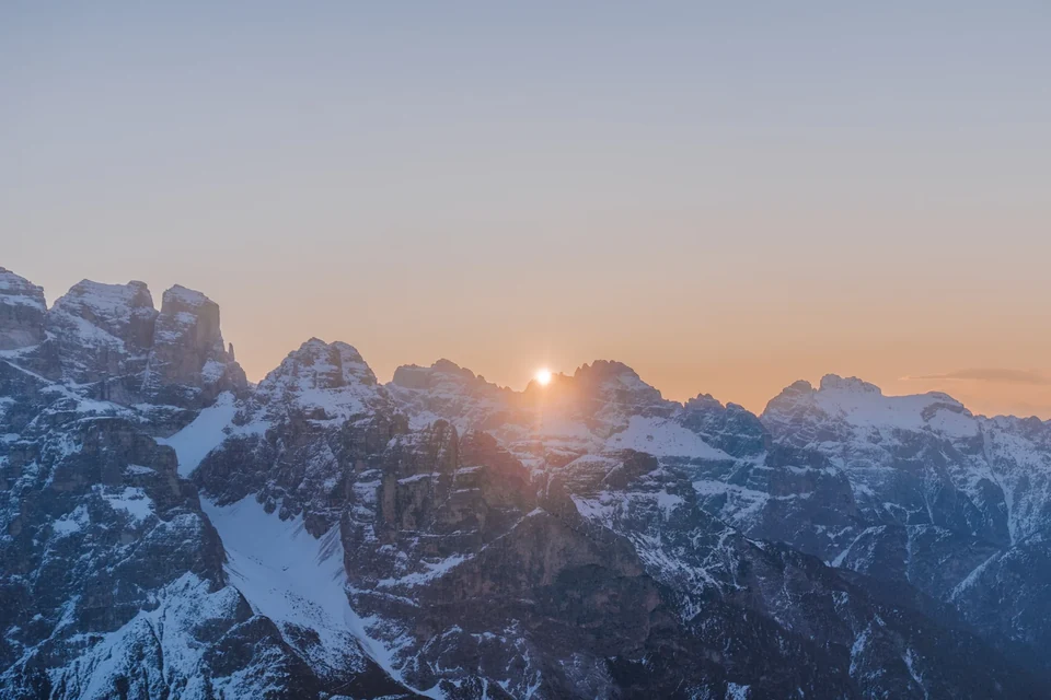 The sun bursting over snow-dusted Dolomite peaks